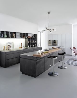A modern kitchen with concrete kitchen slab style cabinets and open shelving and a matching kitchen island