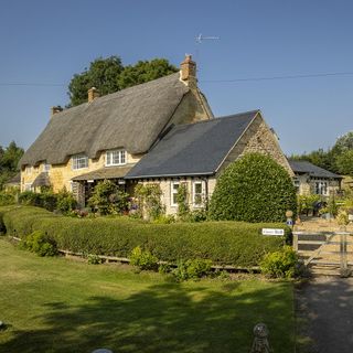 thatched stone house with green lawn