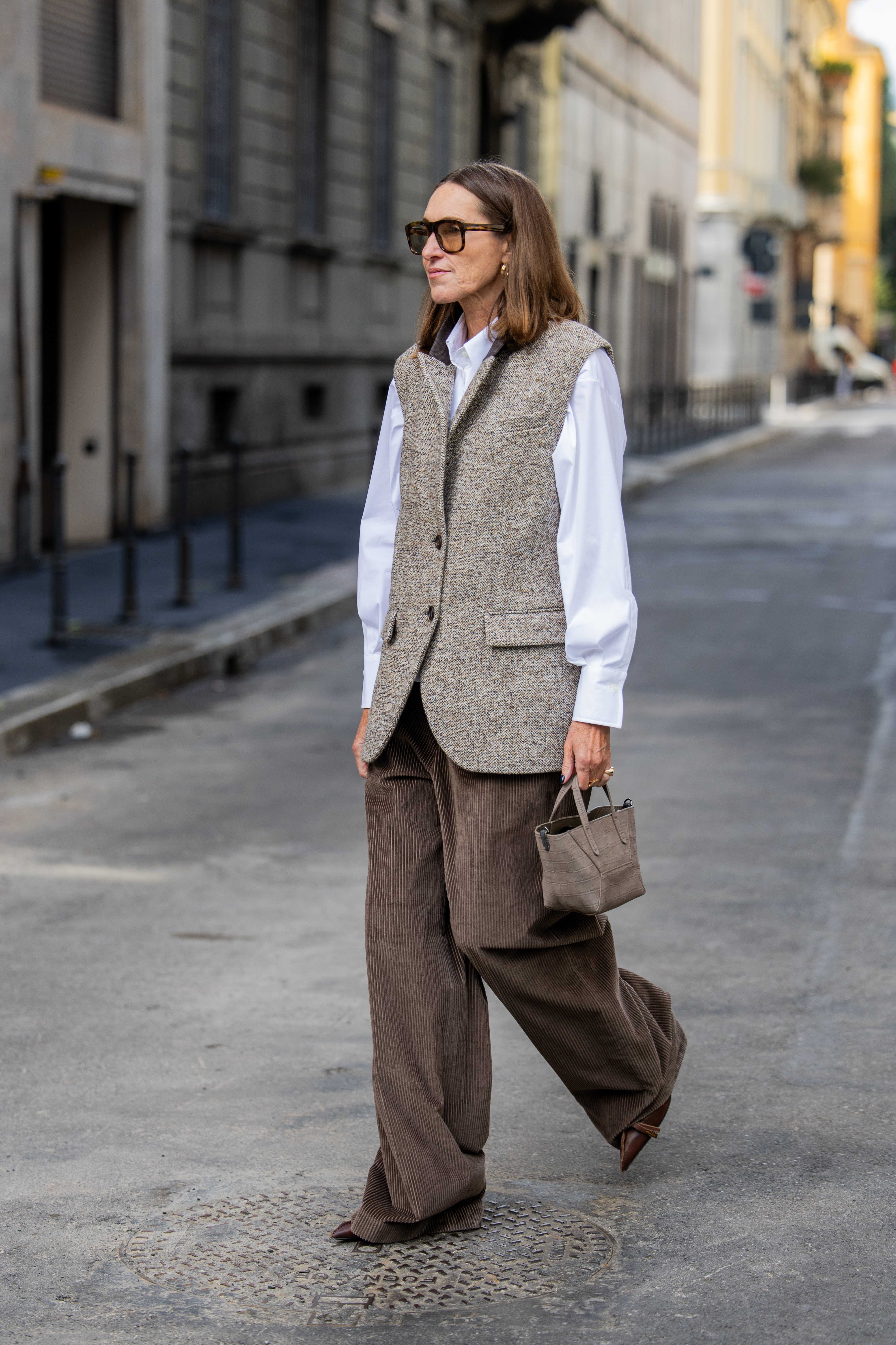 Woman in corduroy pants, a vest, and a button-down.