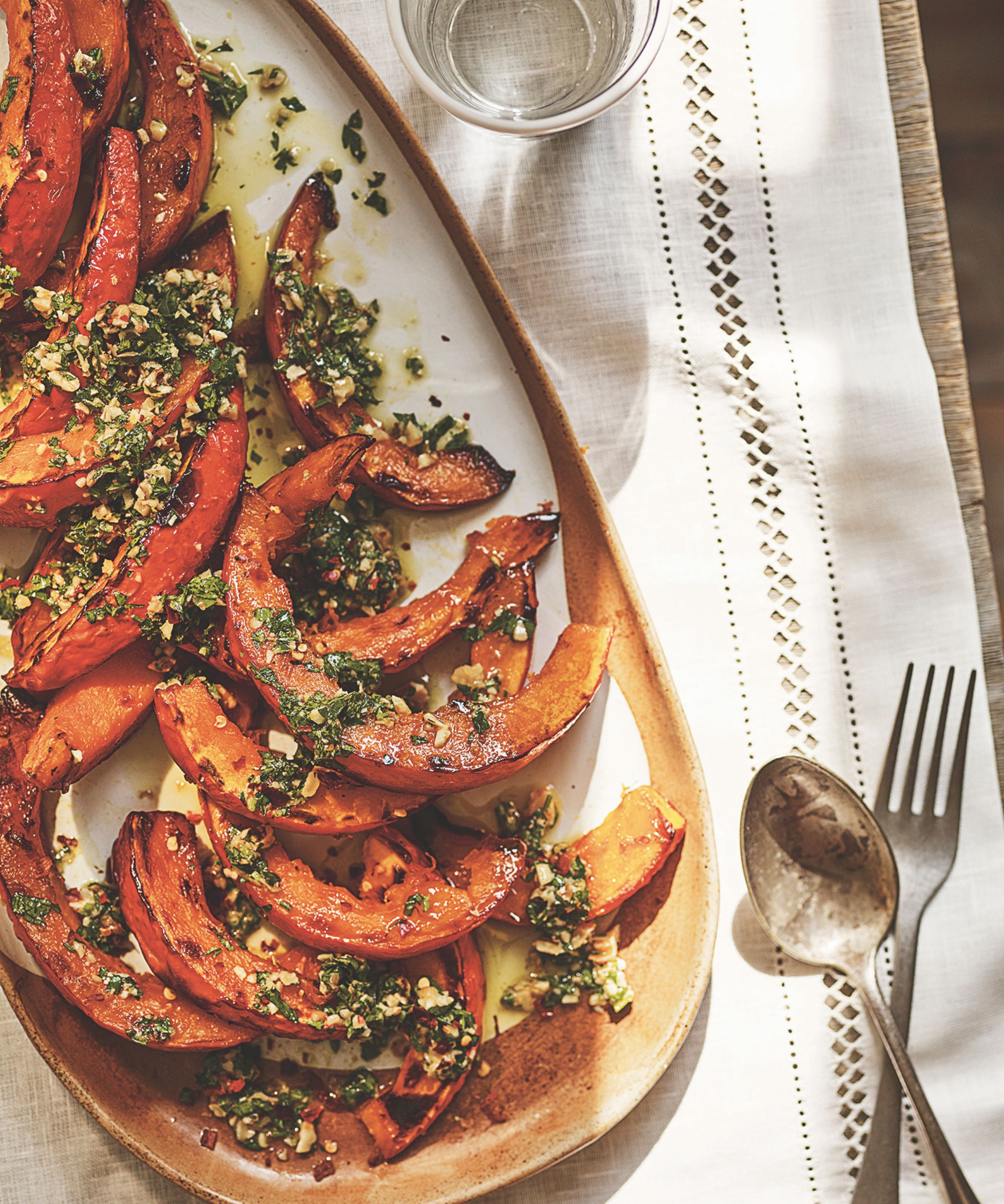 Ceramic platter of roasted pumpkin slices on a white table runner