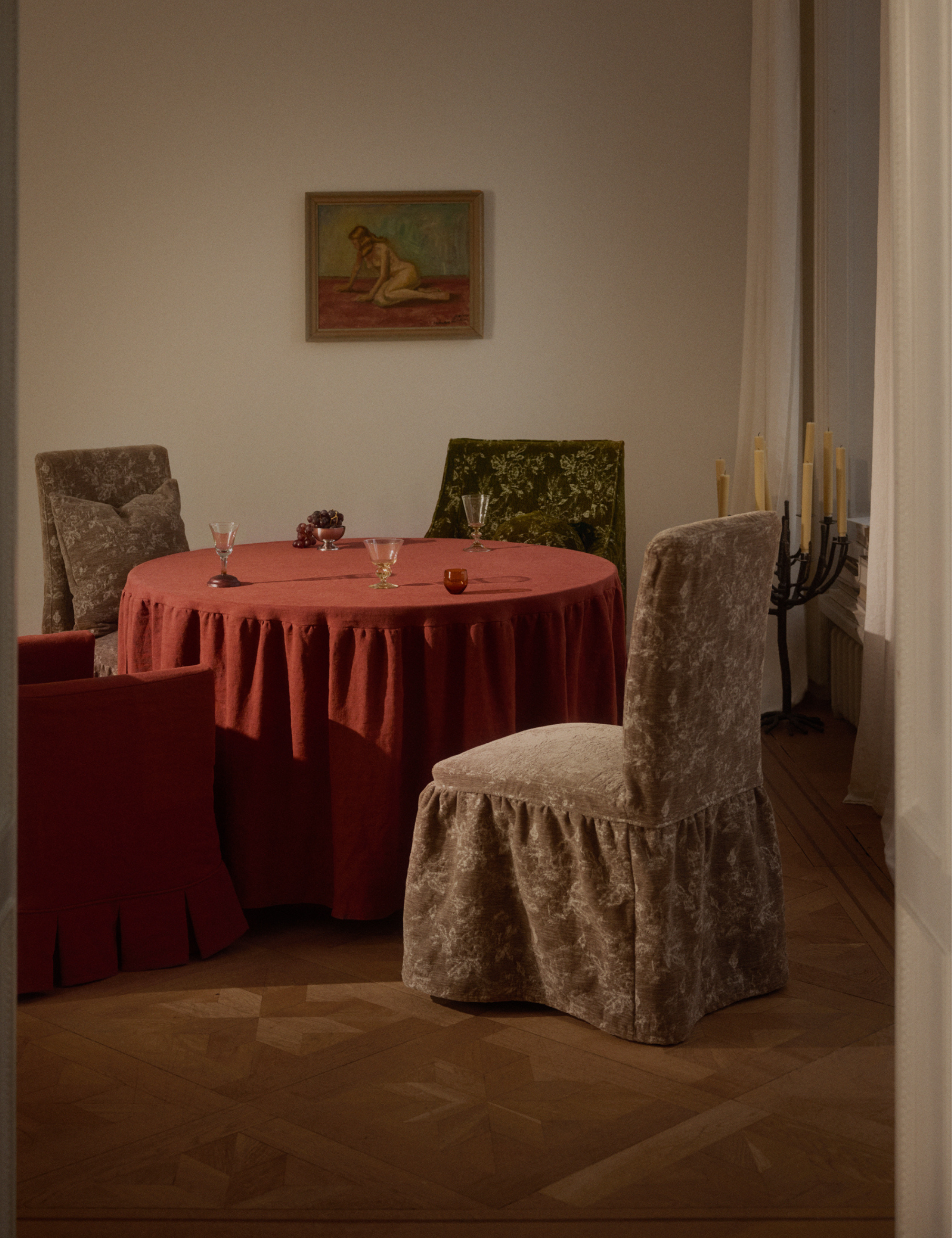 Moody dining room featuring a red skirted dining table alongside four floral-skirted dining chairs