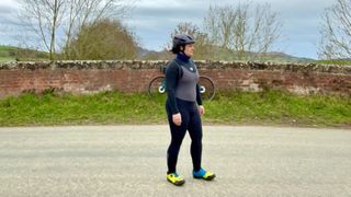 A woman in cycling kit standing near a wall