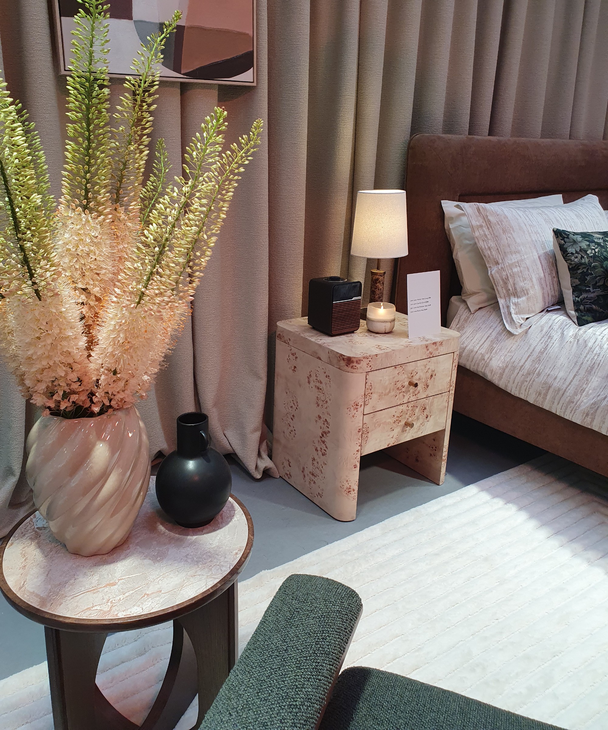 A bedroom set-up at the John Lewis autumn/winter 2025 press preview with a burl bedside table and a brown upholstered bed