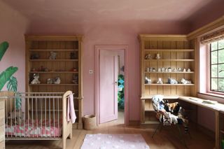 Chalky pink kids bedroom with green plant print and wooden cabinets