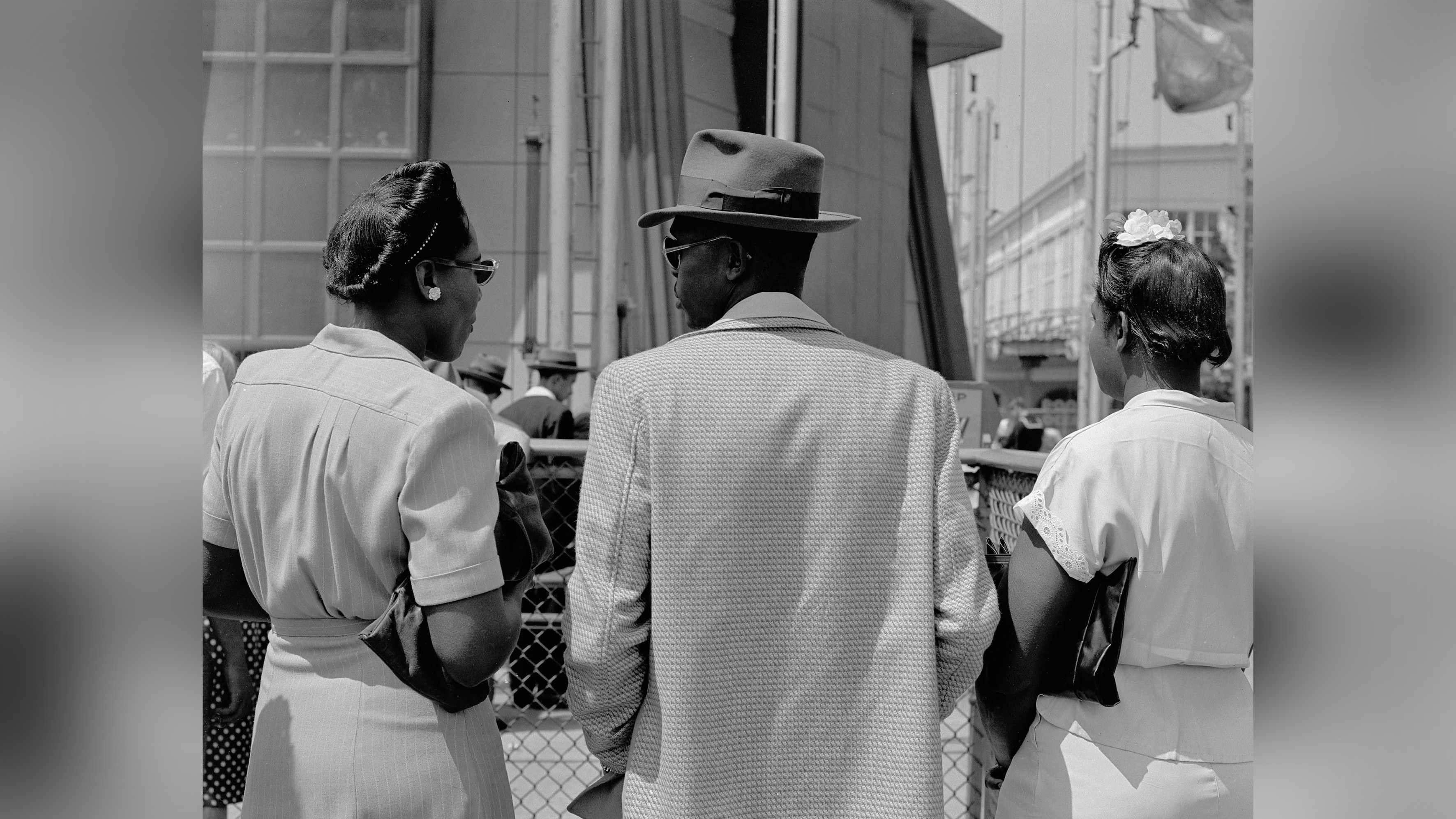 Three African-American people pictured from behind. They are dressed smartly. 