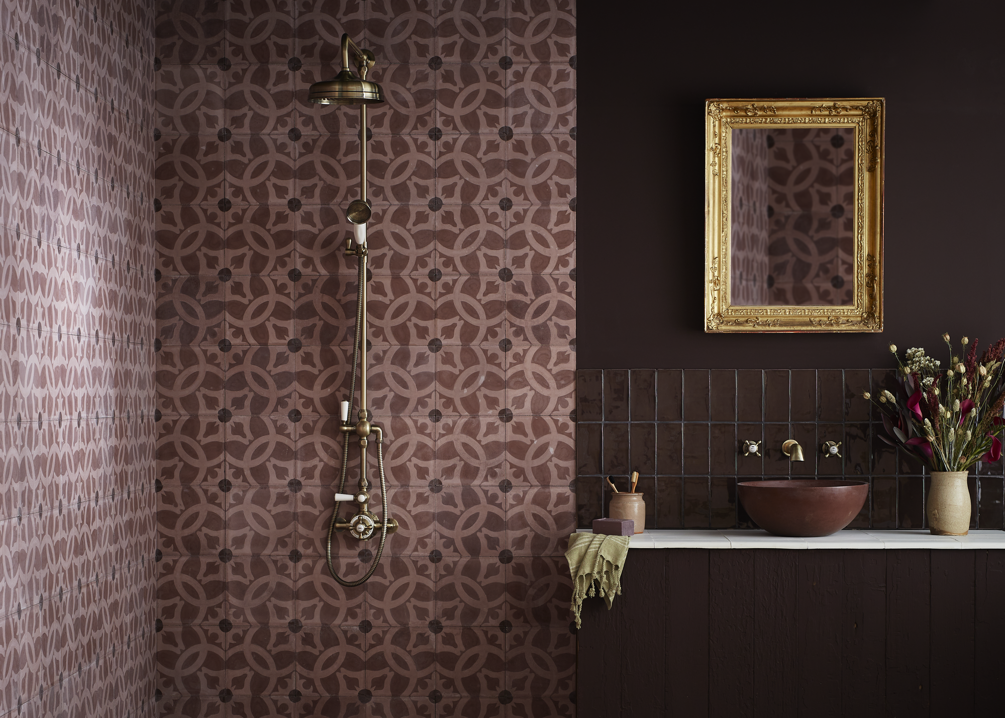 A bathroom with deep purple walls, a patterned tiled shower, and a basin with purple tiles