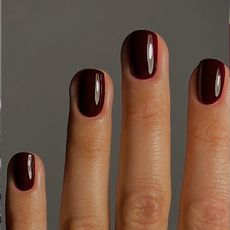 A close up of a short dark red manicure