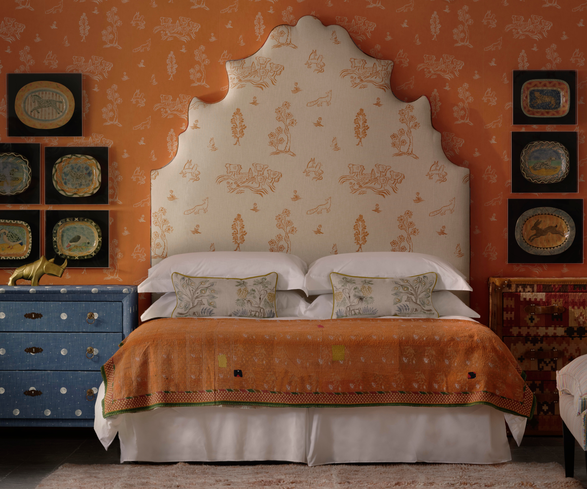 bedroom with orange patterned wallpaper, large cream headboard with same pattern in reverse colours