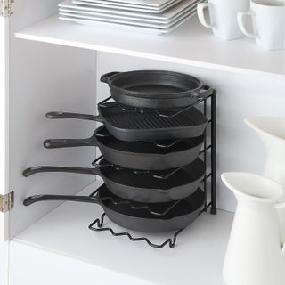 black pans rack with pans in a kitchen cupboard