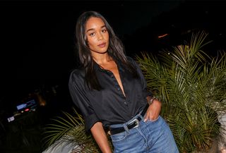 Laura Harrier at the Frame x Amelia Gray Dinner held at Chateau Marmont on April 4, 2024 in Los Angeles, California wearing a black button-down shirt, blue jeans, and a black and silver Western belt.