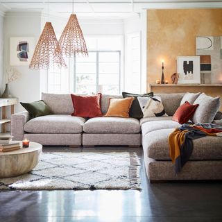 Large grey corner sofa with various colours of throw cushions a rug and coffee table