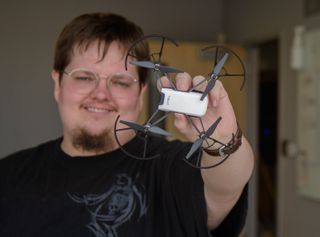 A college student holds a small drone up to the camera