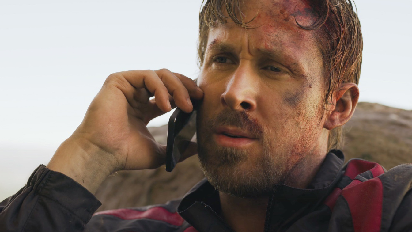 a battered and bruised Ryan Gosling talking into a phone in The Gray Man