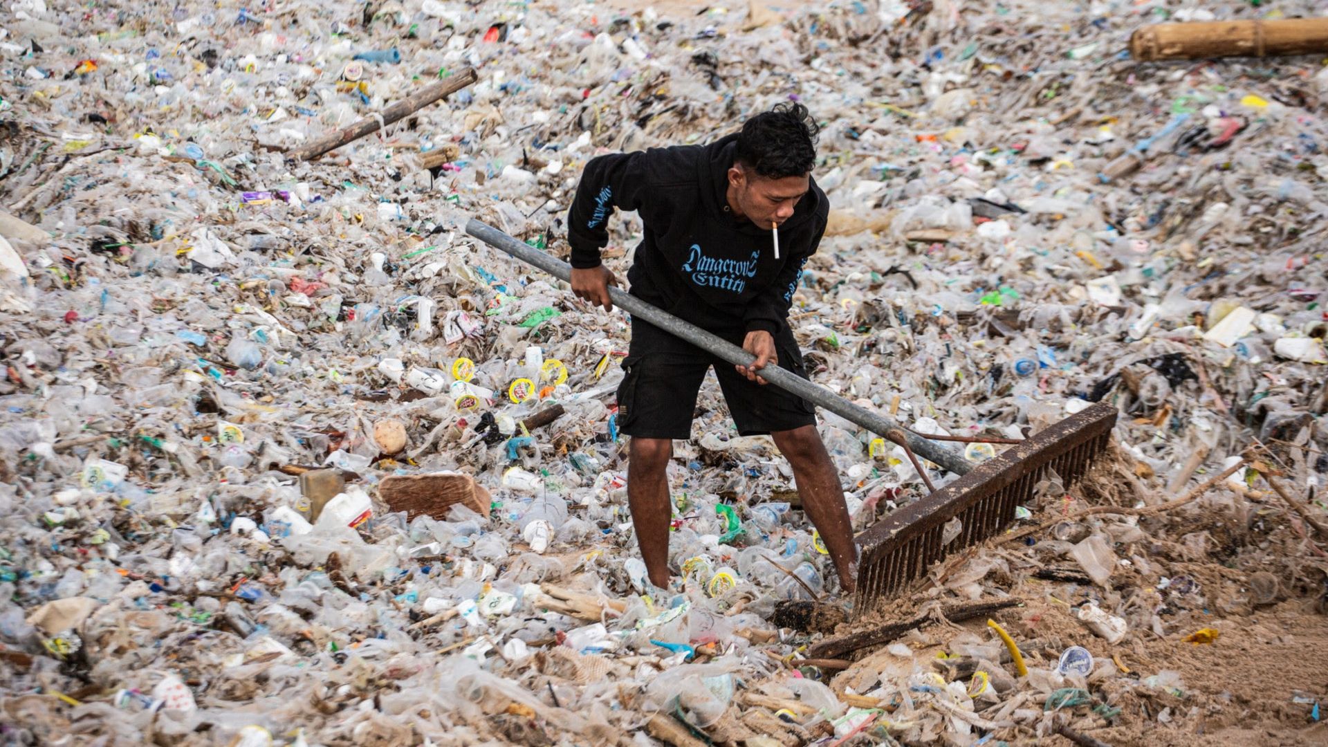 
                                A resident clears marine debris and plastic waste washed ashore during the monsoon season at Jimbaran Beach in Bali, Indonesia
                            