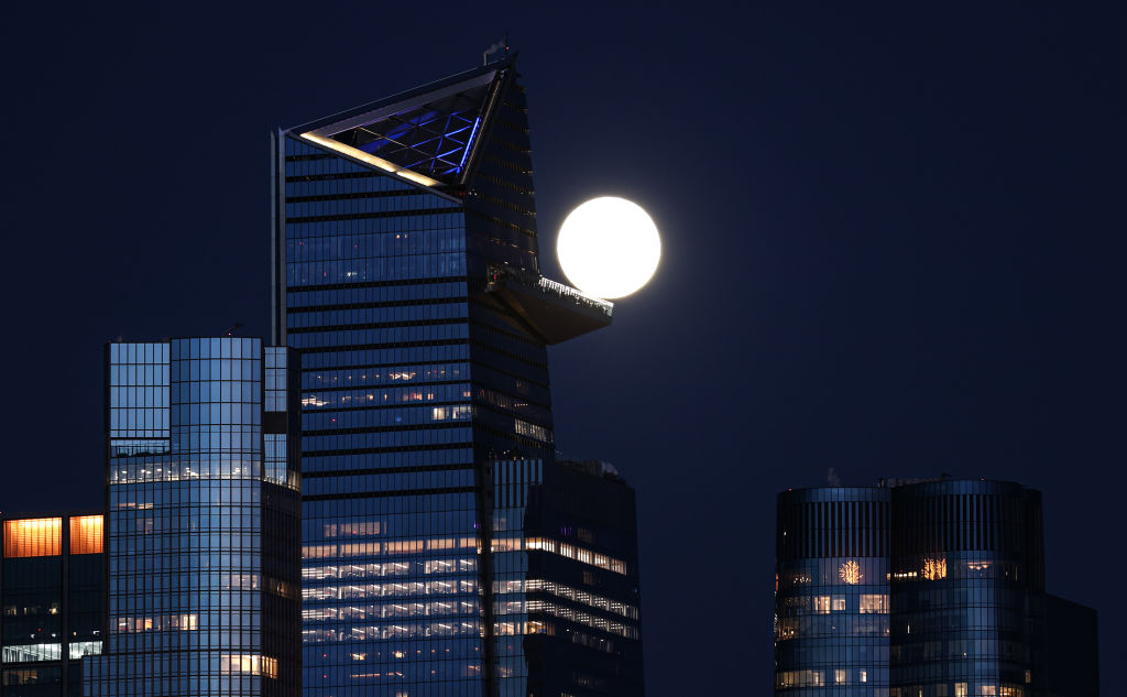 Luna piena luminosa dietro un grattacielo