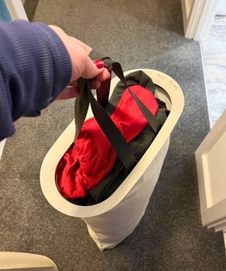 A cream linen bag with black handles showing it is full and out of the organizer ready for laundry