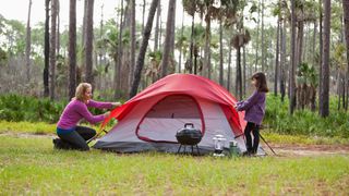 how to camp in the rain: couple setting up wild camp