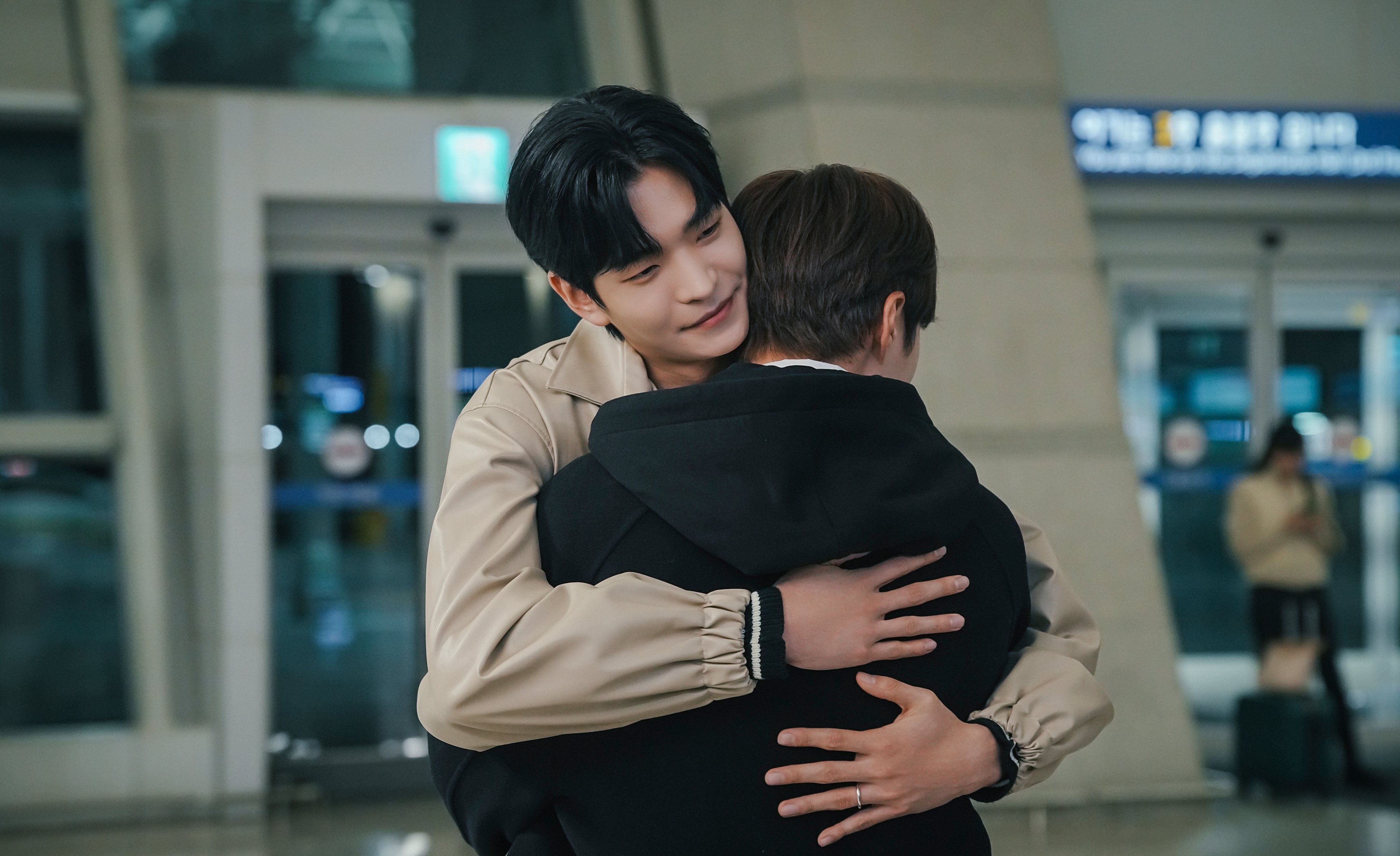 two men hug in the entrance of an airport in a still from the bl kdrama secret relationships