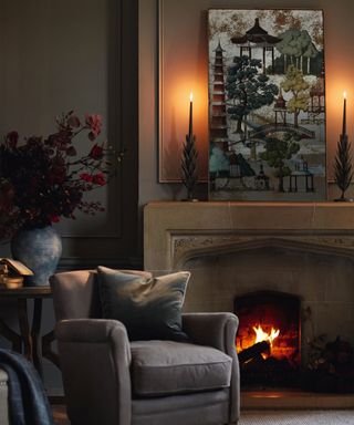Cozy living room, leather armchair beside lit fire, mantel decorated with candles