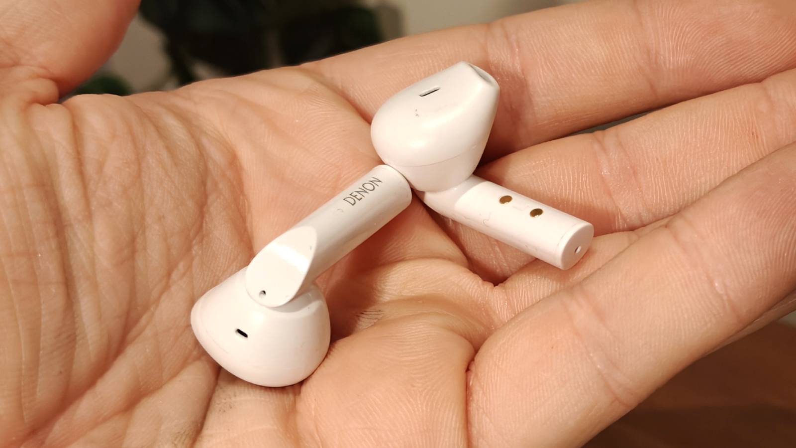 The Denon AH-C500W buds in a hand.