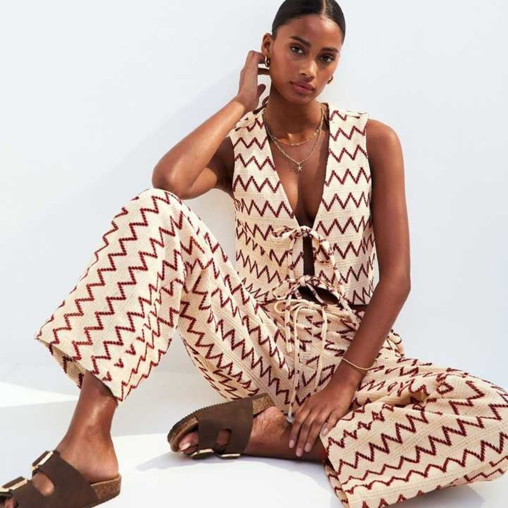 Model wearing a two piece vest and trouser set sold at New Look with brown sandals sat on the floor