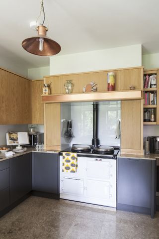 A close up of the kitchen units and cooking area, including a white range cooker and copper cooker hood