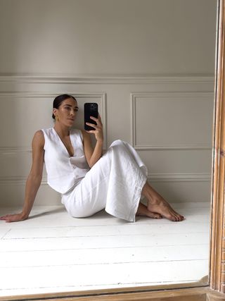 Jessica takes a picture in a mirror wearing a white linen top and skirt set