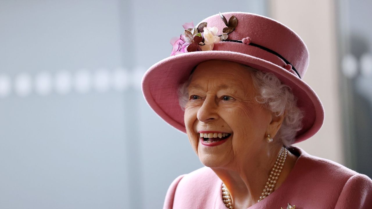 Queen Elizabeth II laughs in a pink suit and matching hat