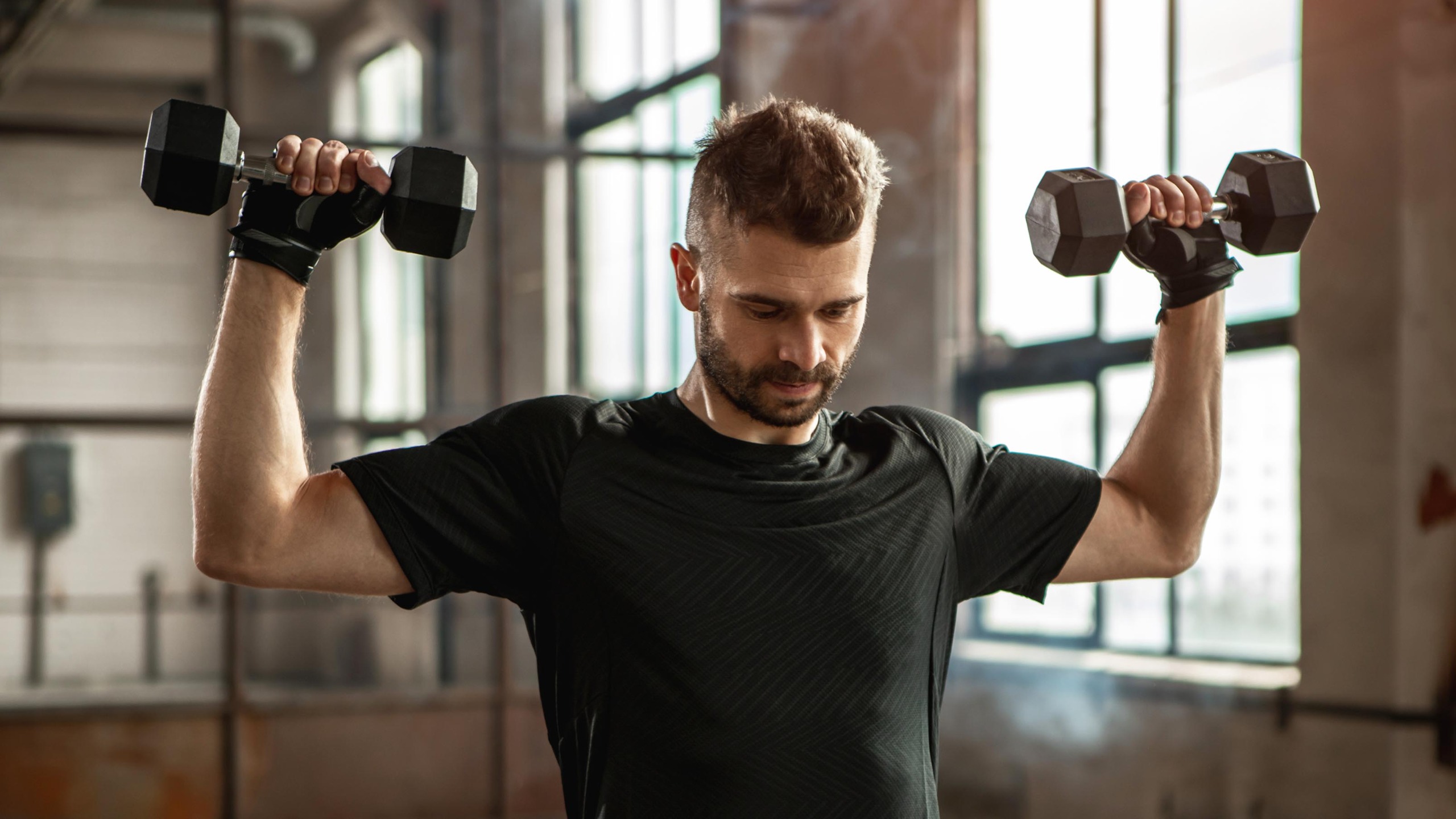 a man holding dumbbells doing an overhead press 