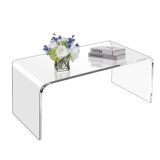 An acrylic coffee table with flowers and books on it