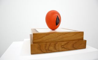 Orange coloured sculpture on wooden boxes
