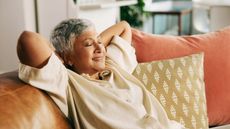 Relaxed senior woman on the sofa smiling with eyes closed