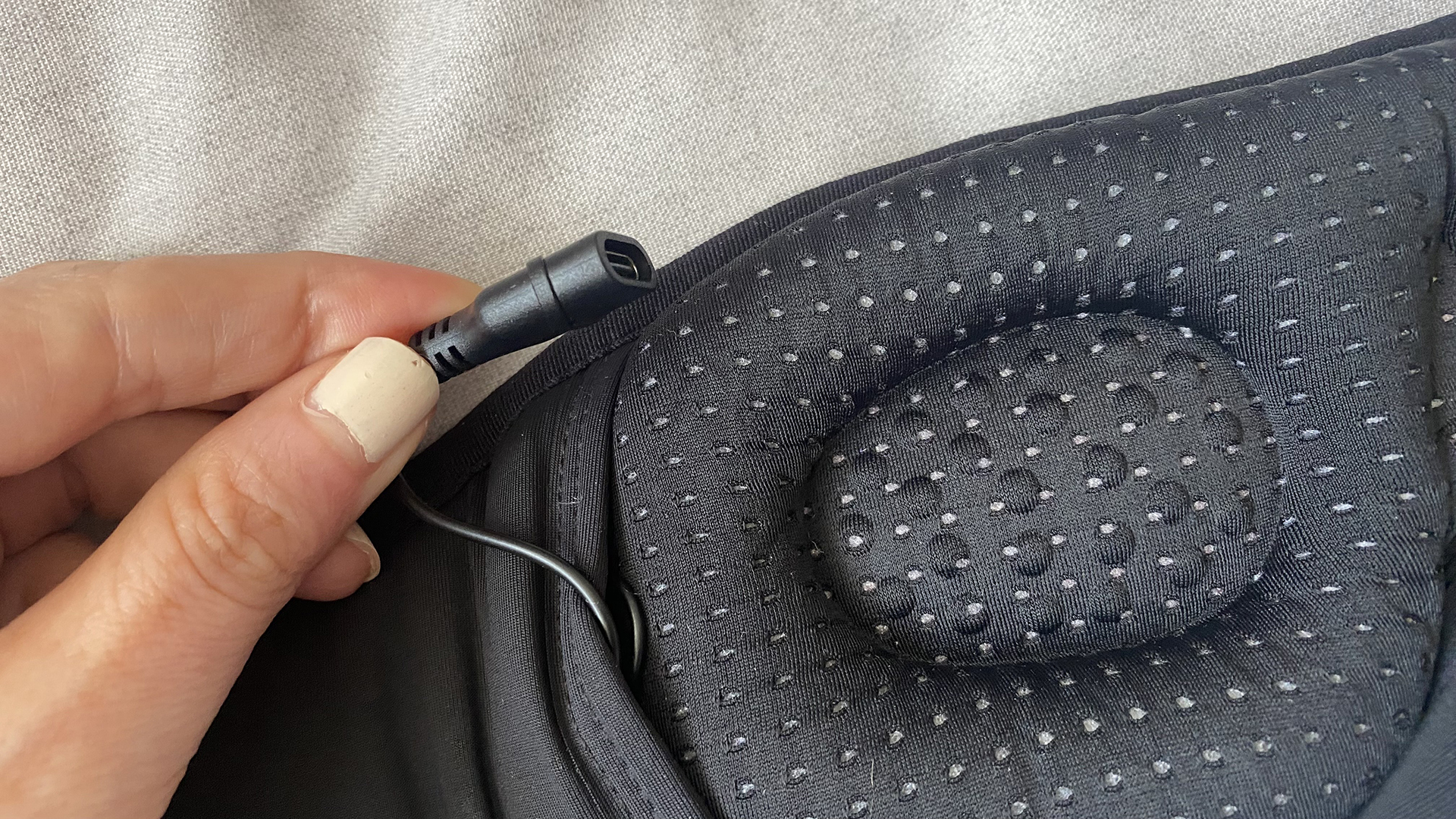 A close up of a hand holding the USB-C charging cable that's integrated into the MUSICOZY Bluetooth sleep mask.
