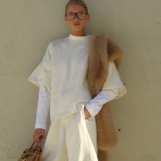 Elsa Hosk wearing a butter yellow sweatshirt and sweatpants with tan boots, a tan fur scarf, and a tan Birkin bag.