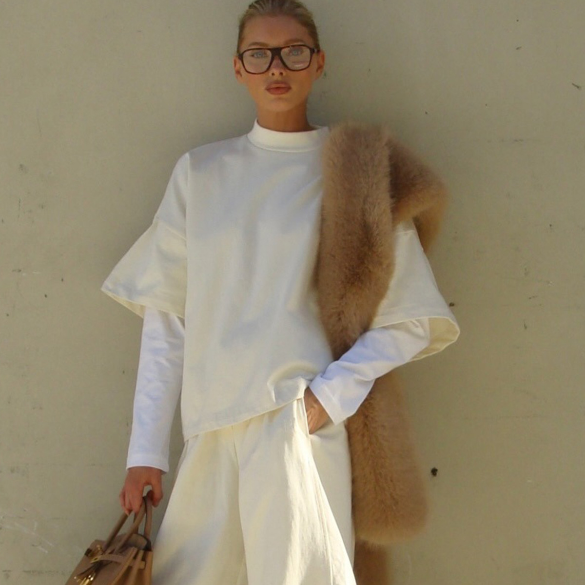 Elsa Hosk wearing a butter yellow sweatshirt and sweatpants with tan boots, a tan fur scarf, and a tan Birkin bag.