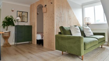 snug with green velvet sofa and slatted wall divider