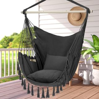 black swinging hammock chair with tassels on a front porch
