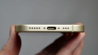 iPhone 15 i en handen med USB-C-porten vänd mot kameran.