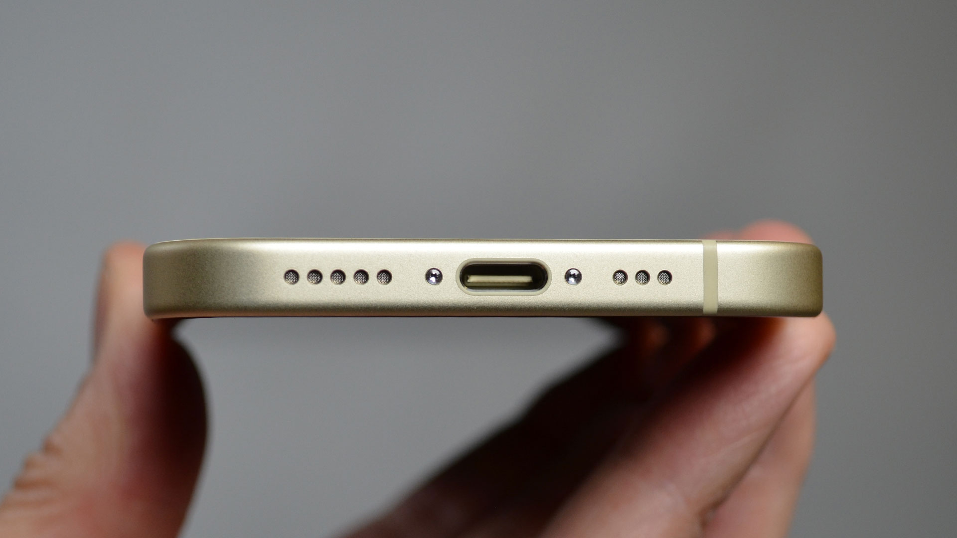 iPhone 15 i en hånd med USB-C porten vendt mot kamera.
