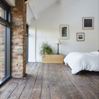 room with white and brick wall and bed and picture frame