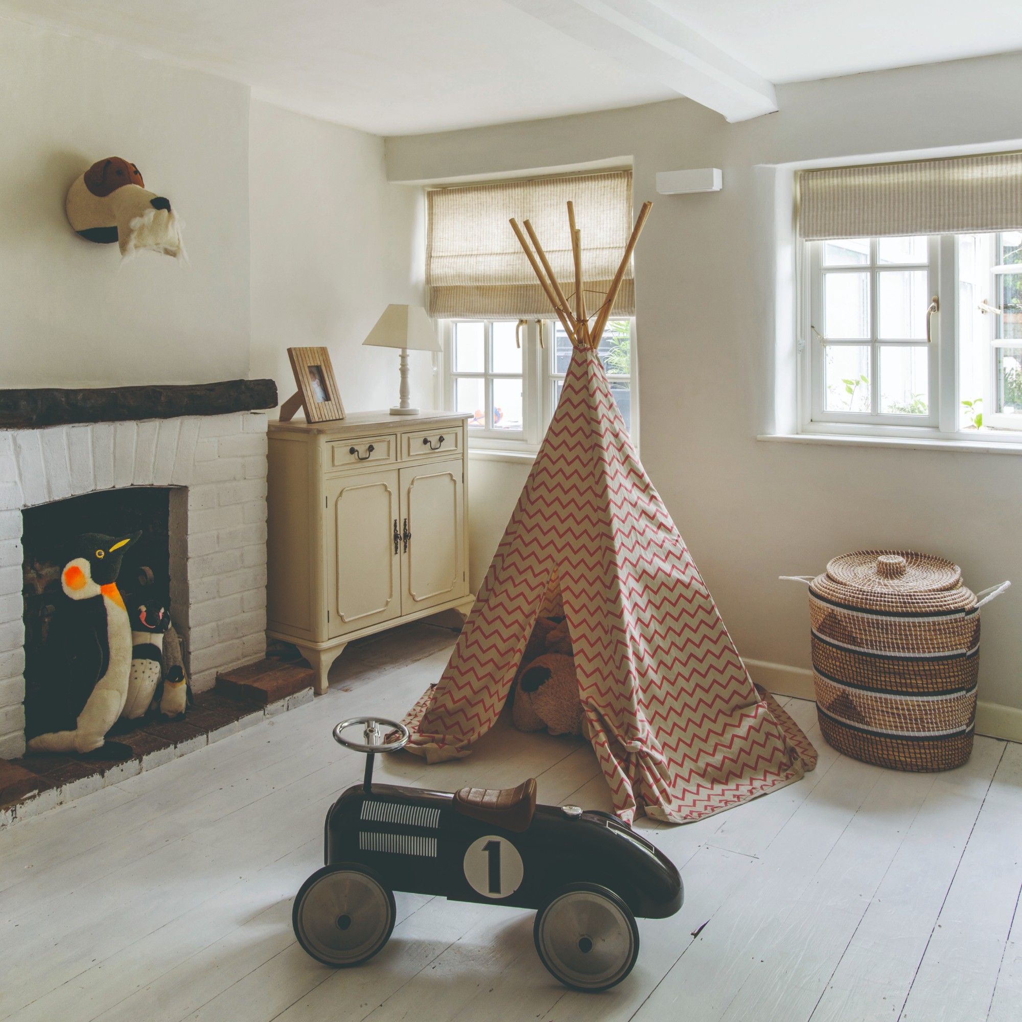 A playroom wih a play teepee, a storage basket and and an old school play car