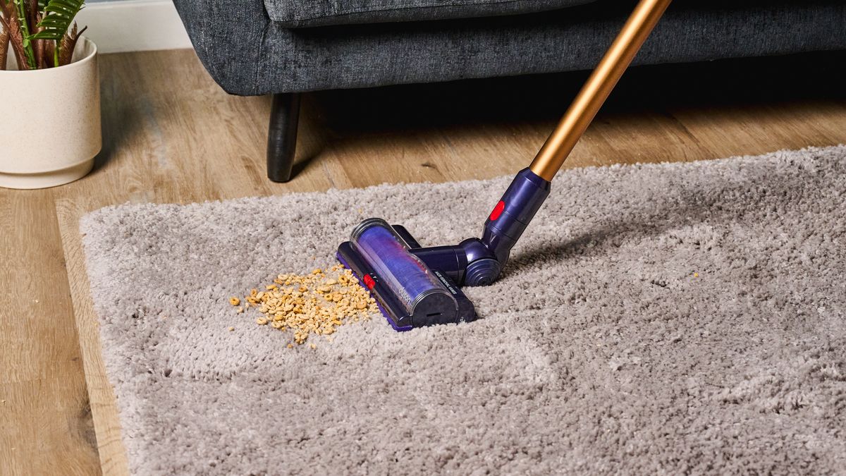 the dyson gen5detect cordless stick vacuum in prussian blue and copper, showing its cleaning head and attachment tools