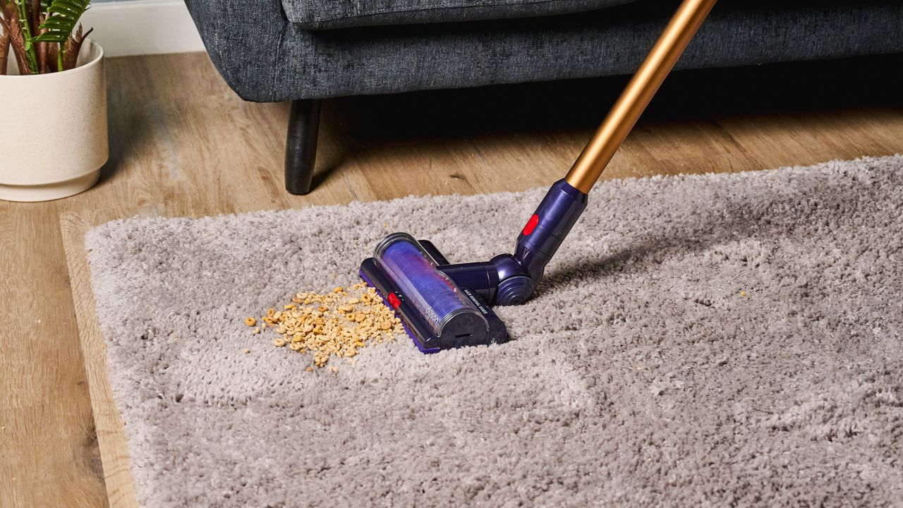 the dyson gen5detect cordless stick vacuum in prussian blue and copper, showing its cleaning head and attachment tools
