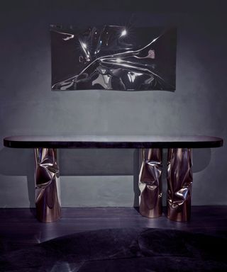 contemporary console table with polished metal legs in room with dark walls