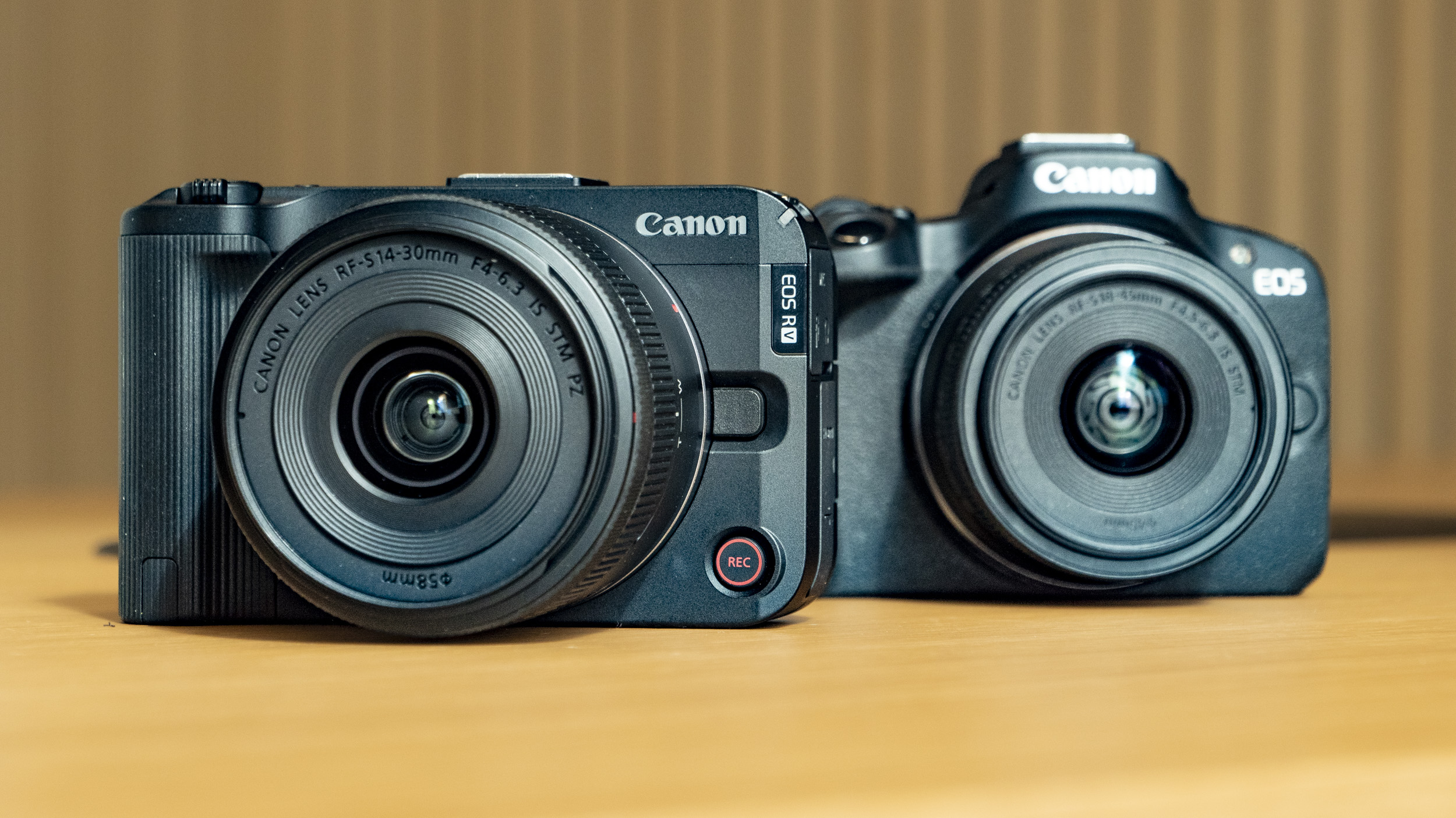 Canon EOS R50 V on a wooden table, alongside the EOS R50