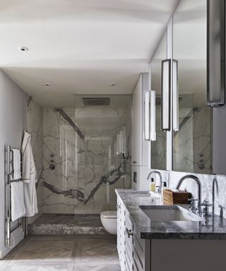 A marble bathroom with a double vanity and wall lights