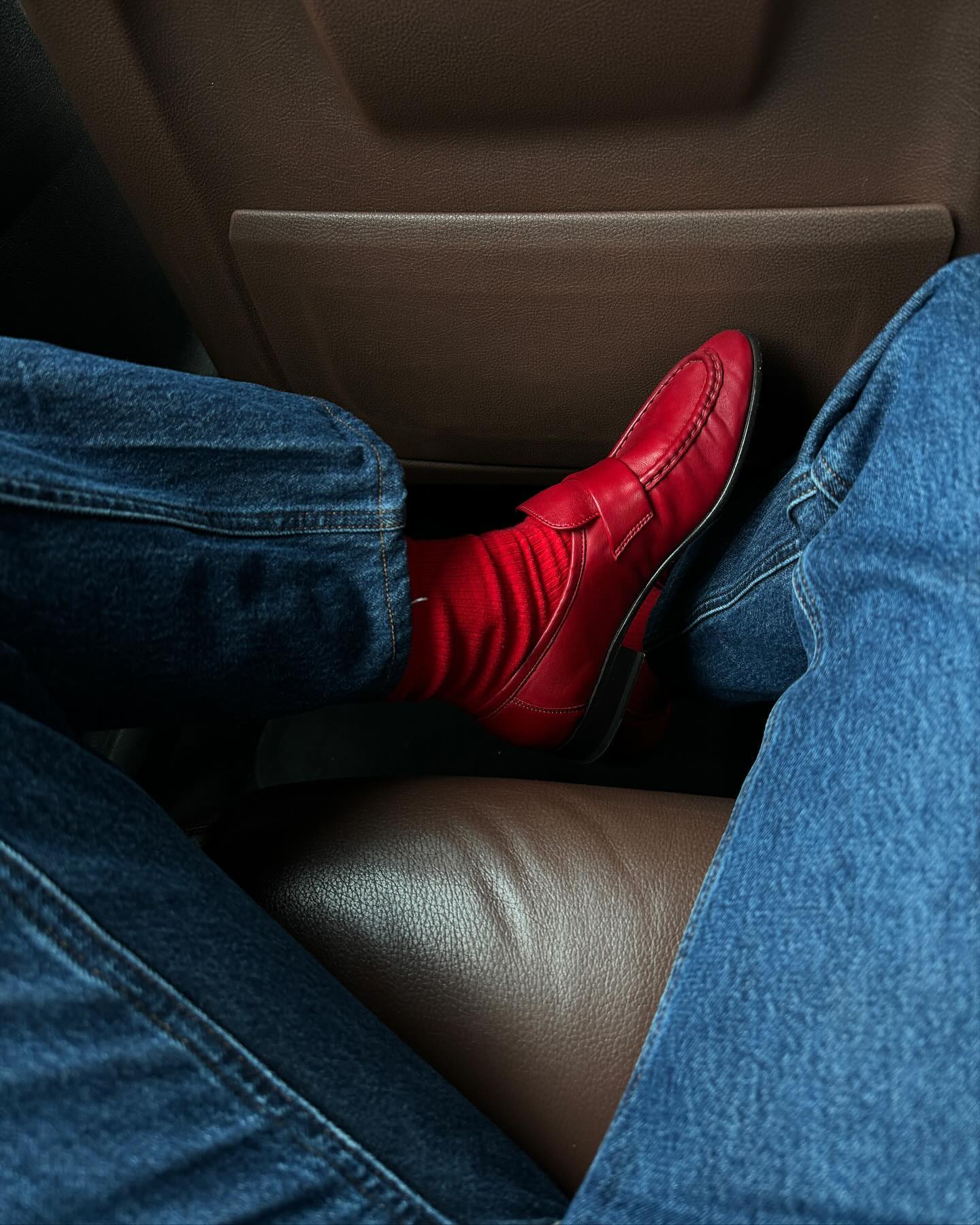 photo of influencer Lucy Williams's legs and feet in a car wearing jeans, red socks, and ATP Atelier red loafers