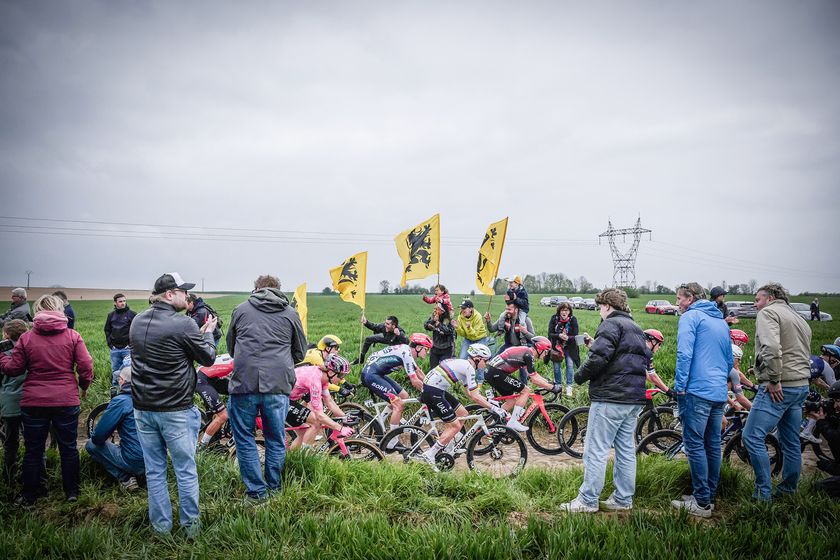 Team Red Bull - Bora - Hansgrohe&#039;s Dutch rider Mick van Dijke (Centre L), UAE Team Emirates&#039; Slovenian rider Tadej Pogacar and Ineos Grenadiers&#039; British rider Ben Swift cycle past spectators holding flags of the Flemish Movement in a paved area during the 122nd edition of the Paris-Roubaix one-day classic cycling race, 259,2 km between Compiegne and Roubaix, northern France on April 13, 2025. (Photo by JEFF PACHOUD / AFP) (Photo by JEFF PACHOUD/AFP via Getty Images)
