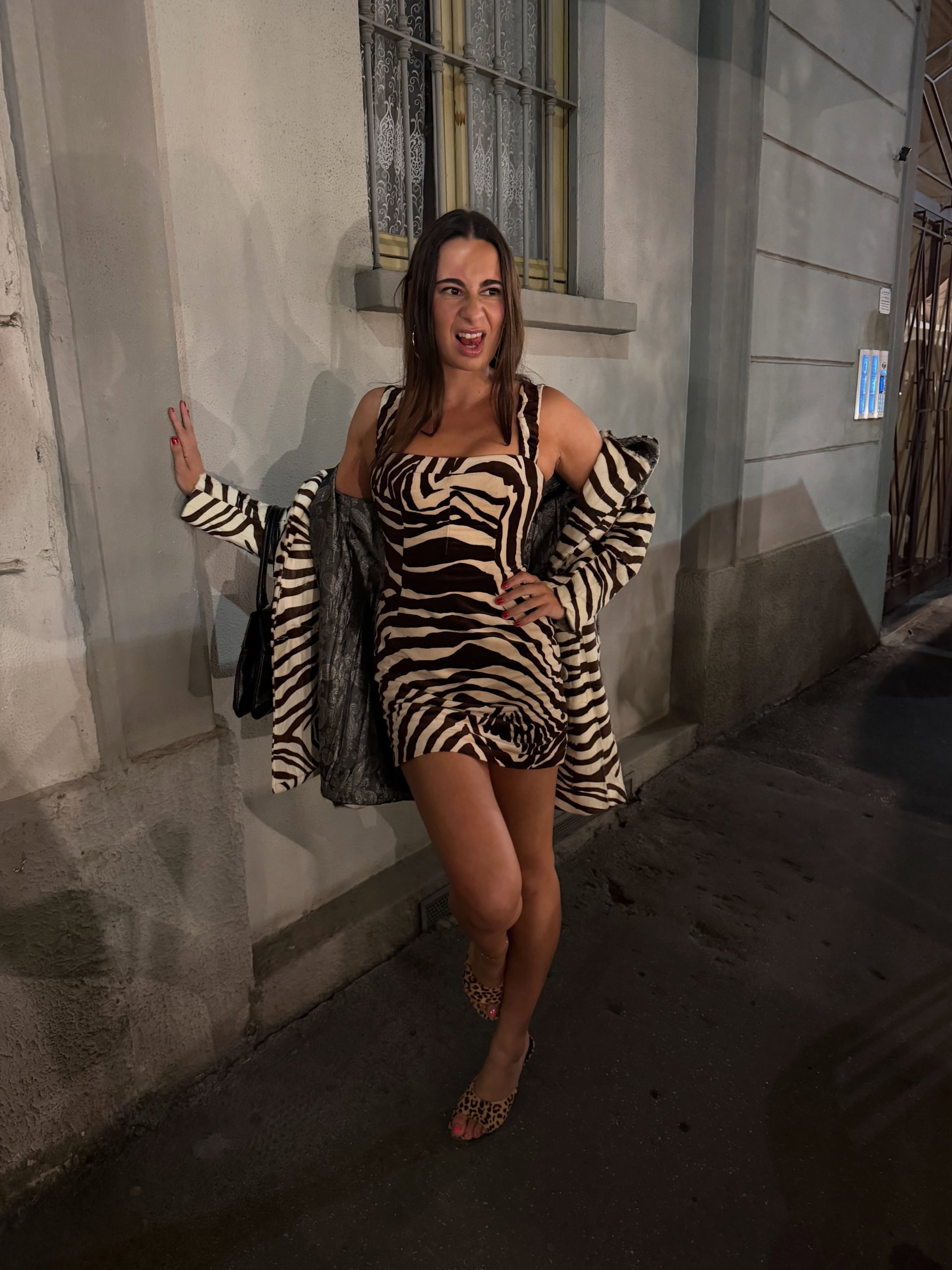 Woman wearing a zebra-print dress and matching coat.