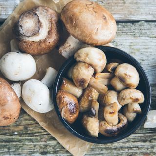 Various types of raw and cooked mushrooms on table and in bowl